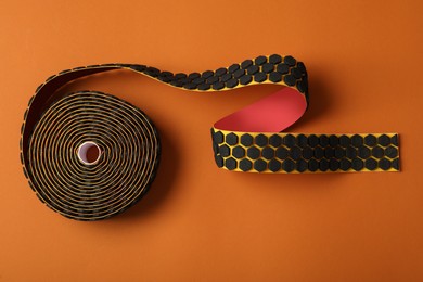 Bright kinesio tape in roll on brown background, top view