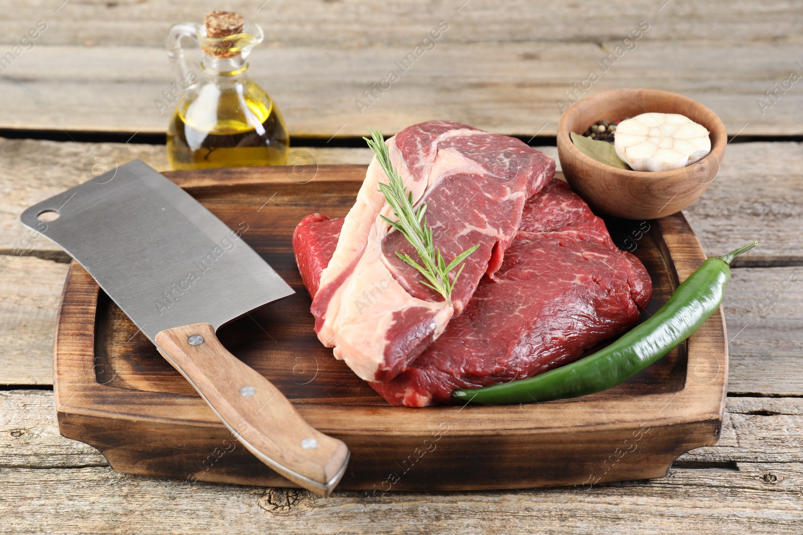 Photo of Fresh raw beef cut, spices and butcher knife on wooden table