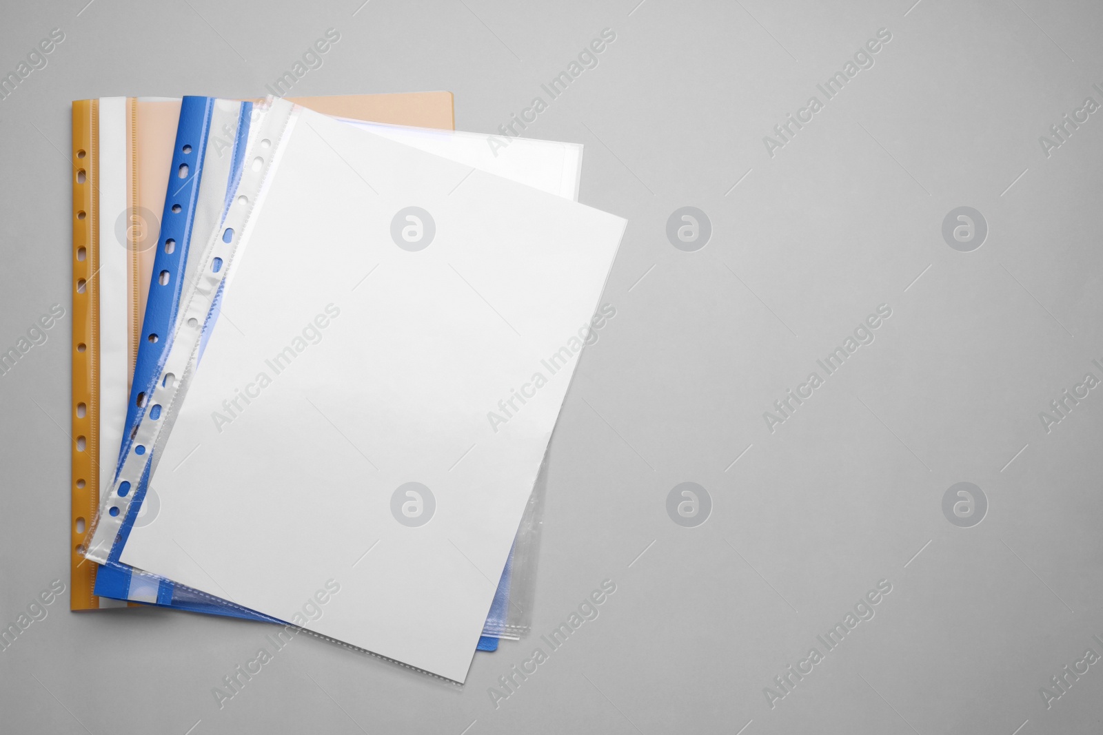 Photo of File folders with punched pockets and paper sheets on light grey background, flat lay. Space for text