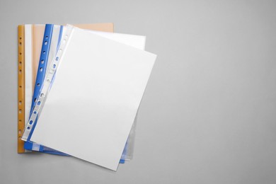 File folders with punched pockets and paper sheets on light grey background, flat lay. Space for text