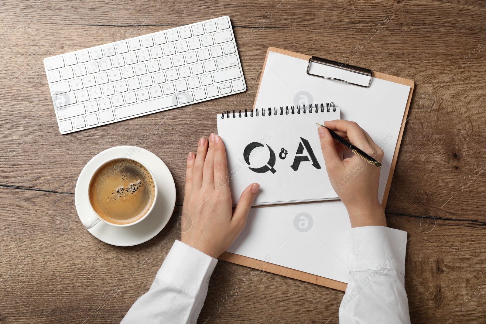 Photo of Woman writing text Q&A in notebook at wooden table, top view