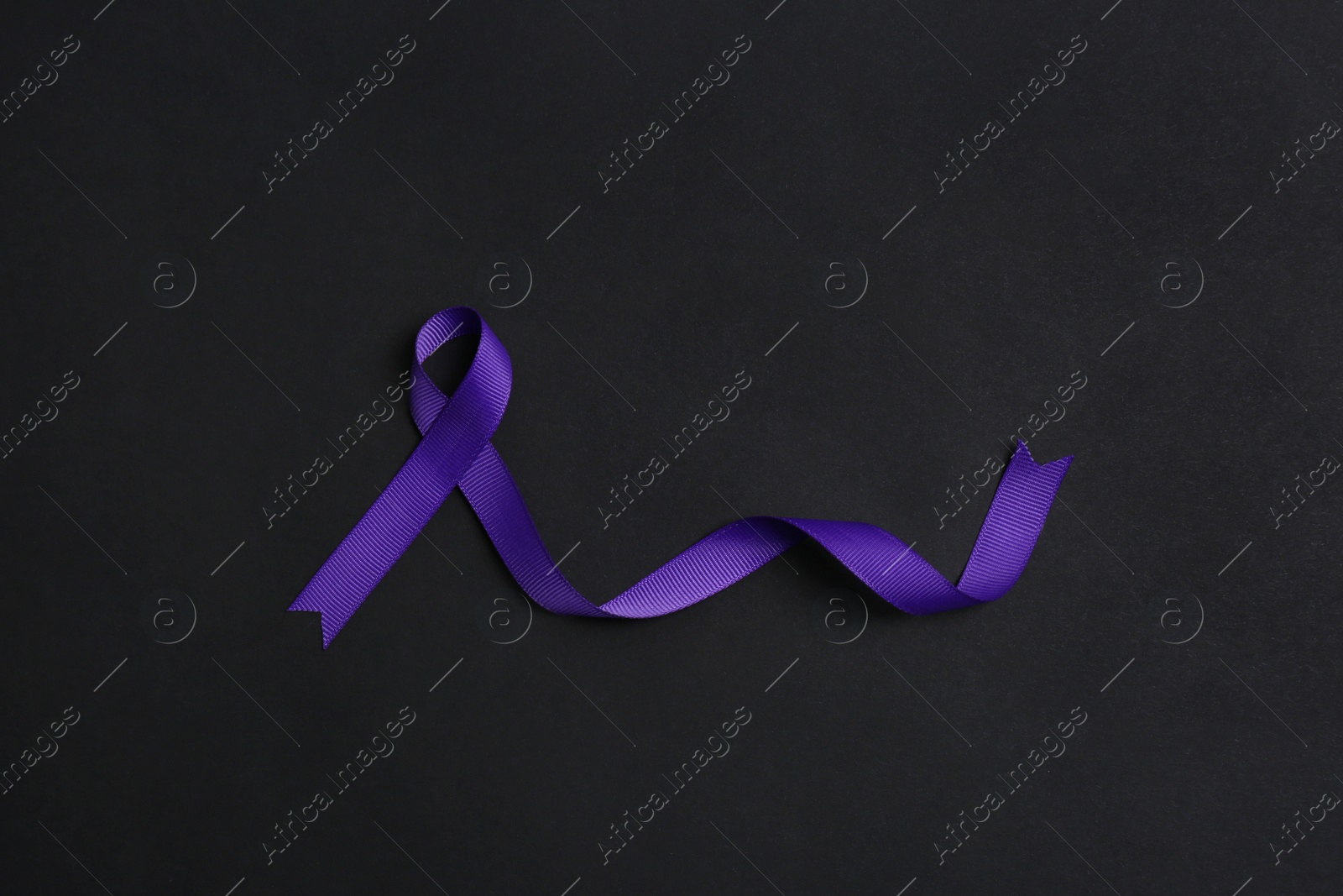 Photo of Purple awareness ribbon on black background, top view