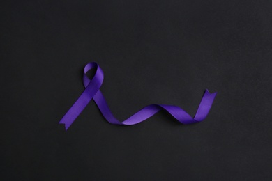 Purple awareness ribbon on black background, top view