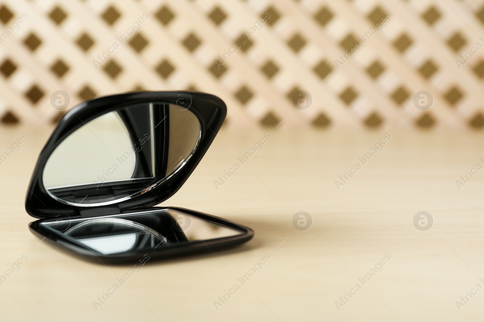 Photo of Stylish cosmetic pocket mirror on wooden table. Space for text