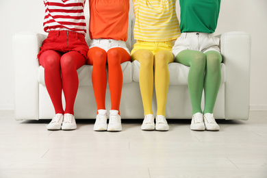 Women wearing bright tights sitting on sofa indoors, closeup
