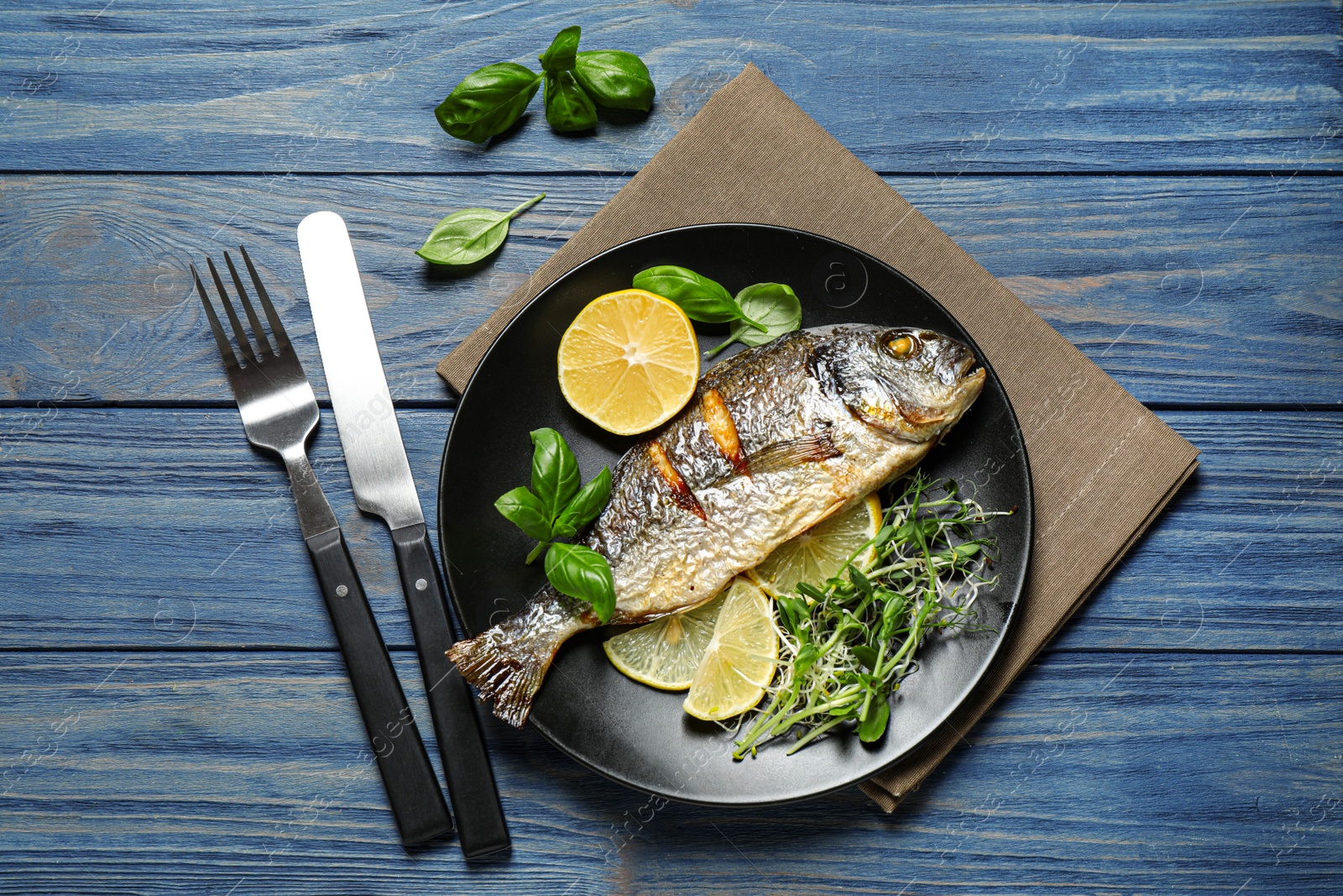 Photo of Delicious roasted fish with lemon on blue wooden table, flat lay