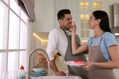 Happy lovely couple washing dishes in kitchen