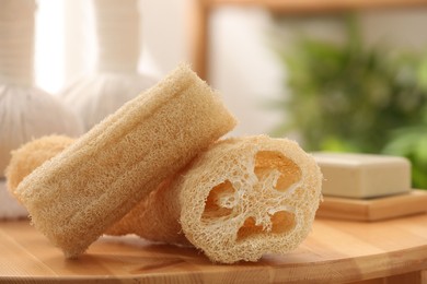 Loofah sponges on wooden table indoors, closeup