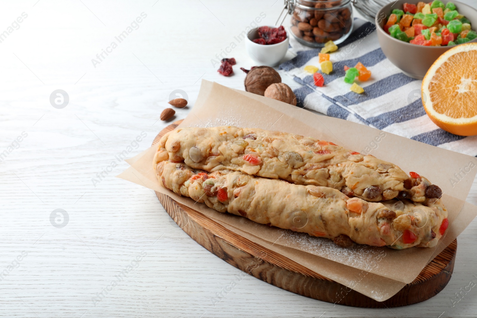 Photo of Unbaked Stollen with candied fruits and raisins on white wooden table. space for text