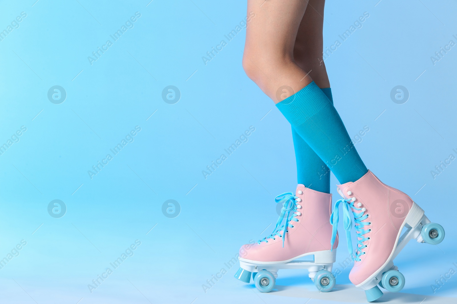 Photo of Woman with vintage roller skates on color background, closeup. Space for text