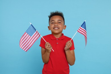 4th of July - Independence Day of USA. Happy boy with American flags on light blue background