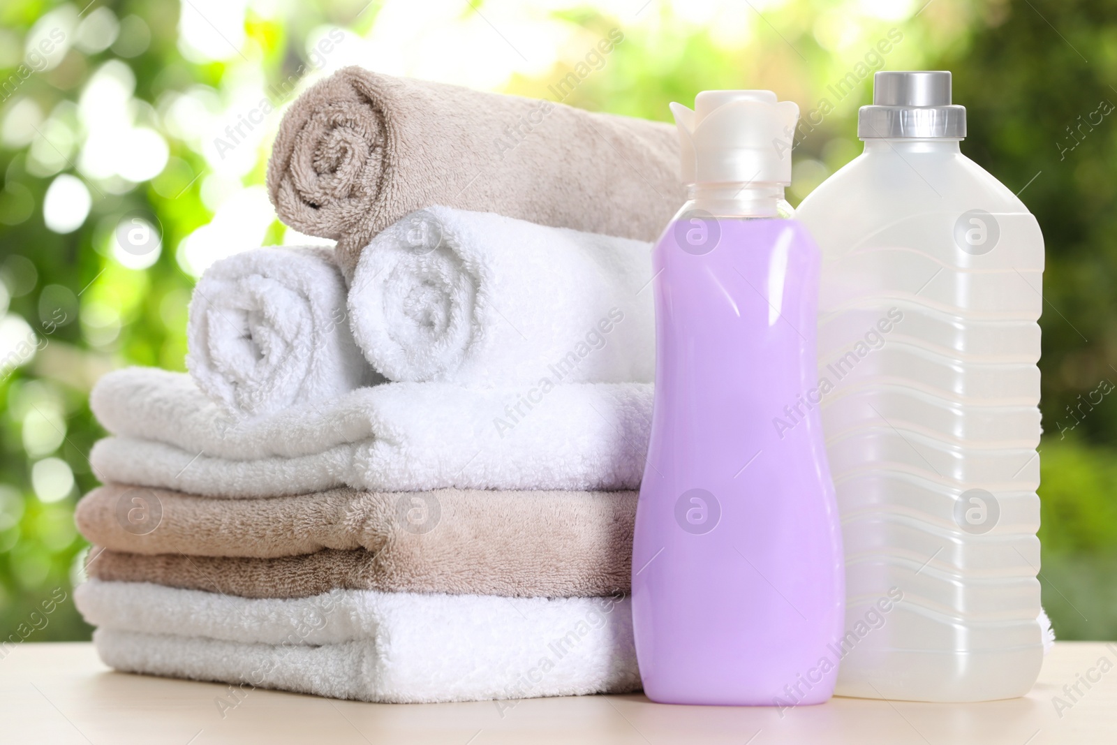 Photo of Soft bath towels and laundry detergents on table against blurred background