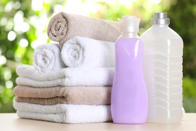 Photo of Soft bath towels and laundry detergents on table against blurred background