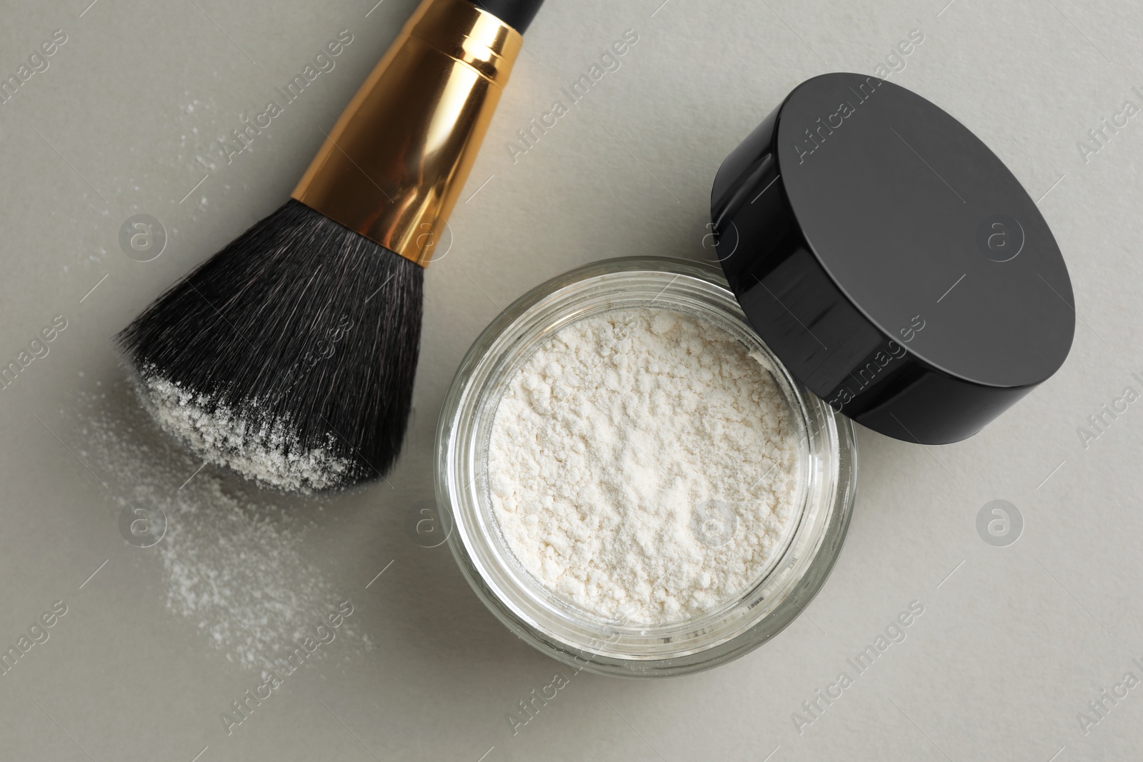 Photo of Rice loose face powder and makeup brush on light grey background, flat lay