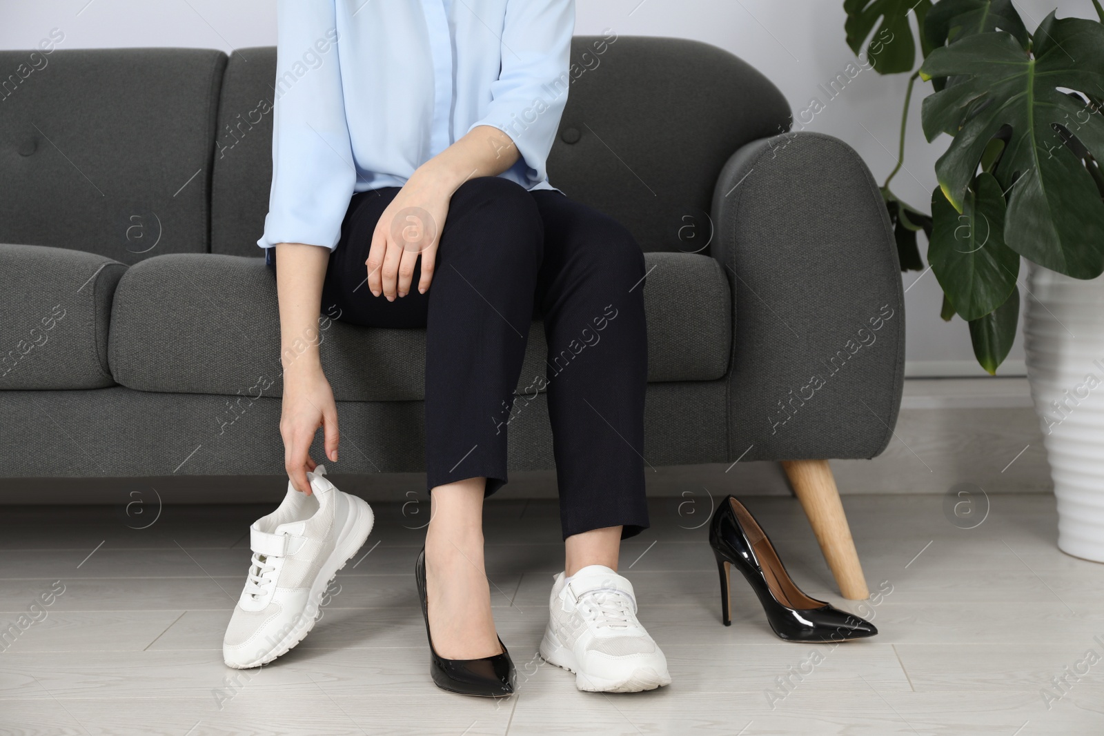 Photo of Woman changing shoes on sofa in office, closeup