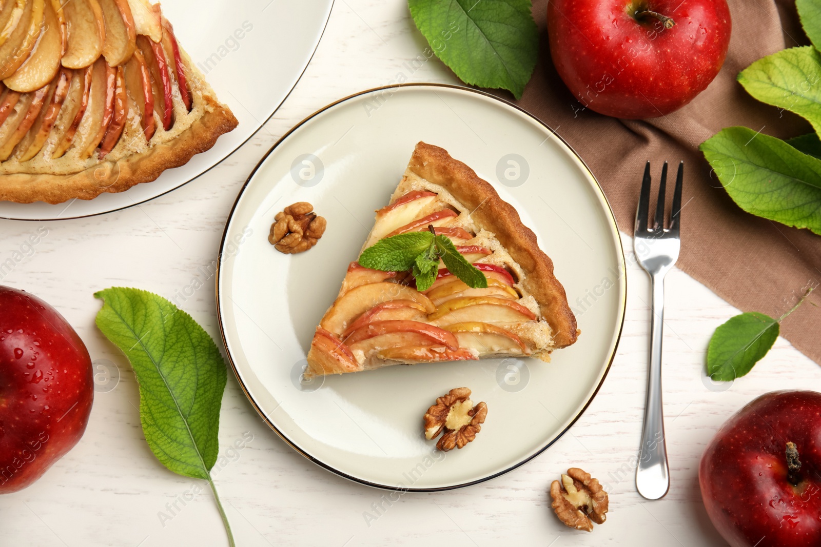 Photo of Delicious apple pie, leaves and fruits on white wooden table, flat lay