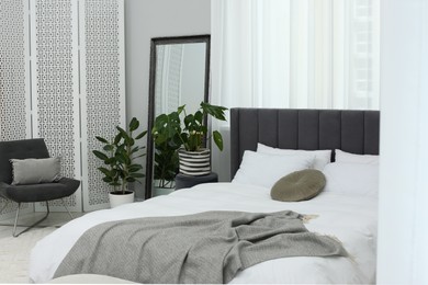 Photo of Large comfortable bed and beautiful houseplants in room. Bedroom interior