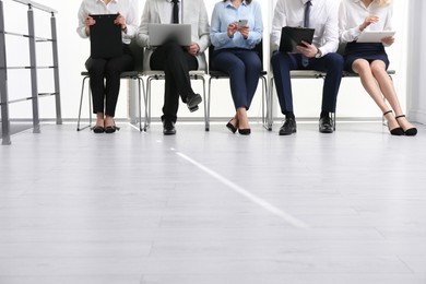 Photo of People waiting for job interview in office hall, closeup