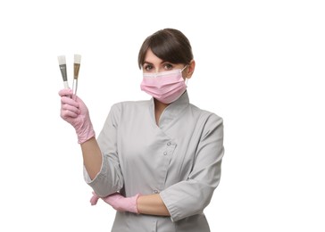 Cosmetologist with cosmetic brushes on white background