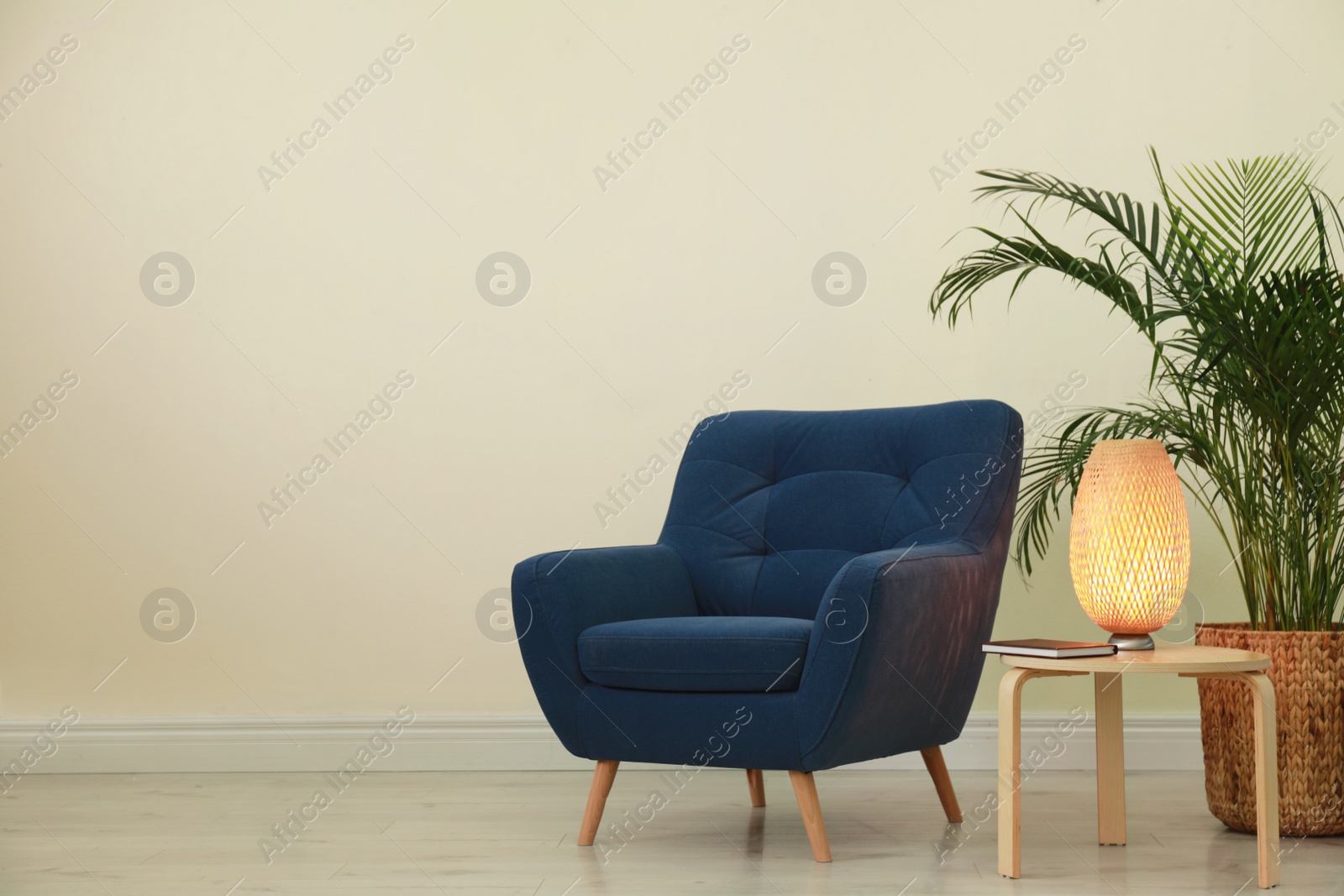 Photo of Stylish room interior with comfortable armchair and plant near beige wall. Space for text