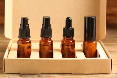 Photo of Bottles with oil in box on wooden table, closeup. Natural cosmetics