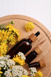 Photo of Glass bottles of essential oil and different wildflowers on white wooden table, top view