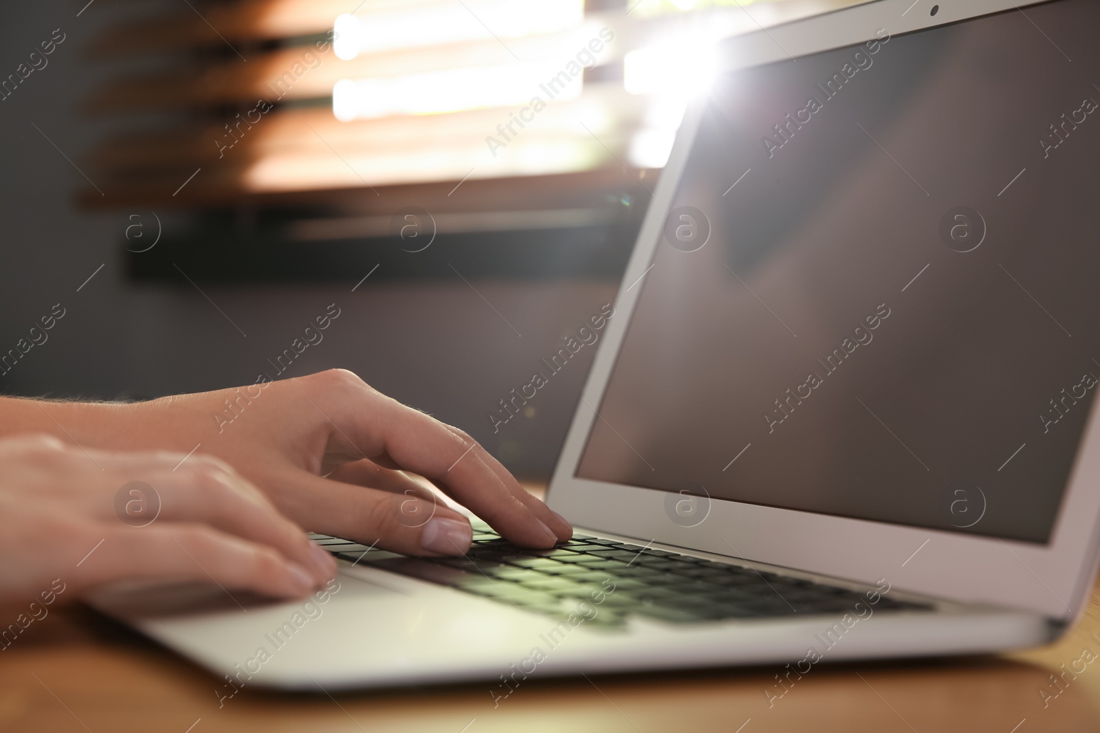 Photo of Woman using modern laptop at table indoors, closeup