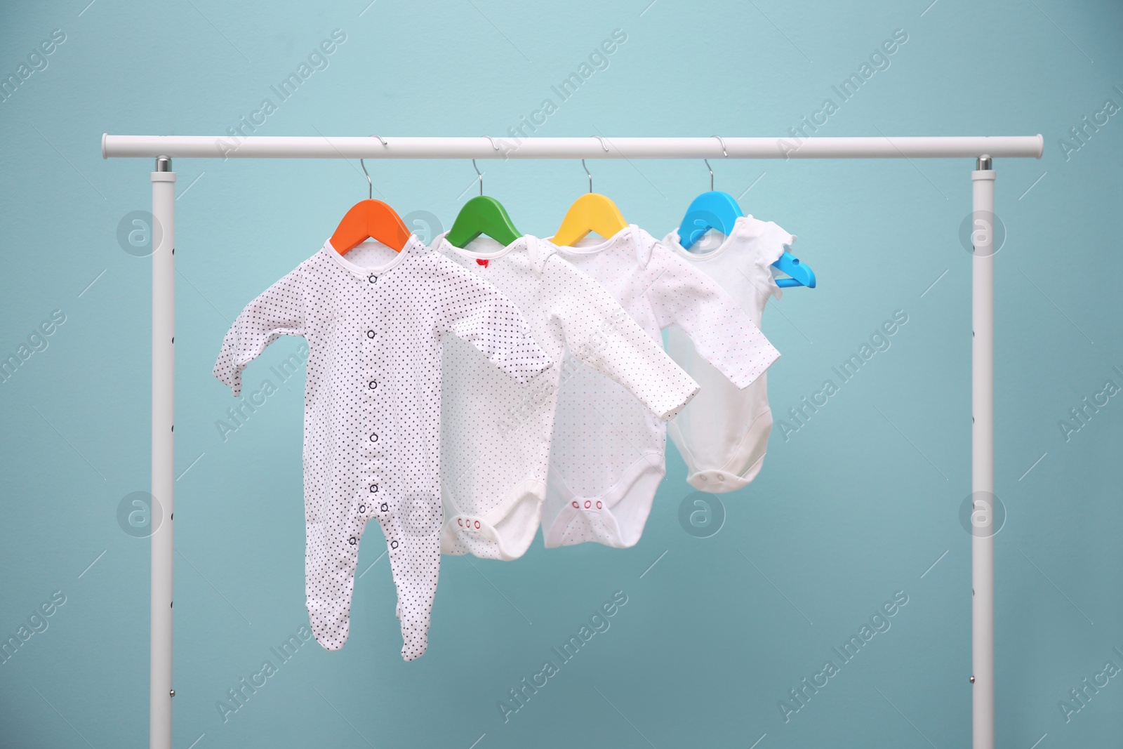 Photo of Baby clothes hanging on rack against color background