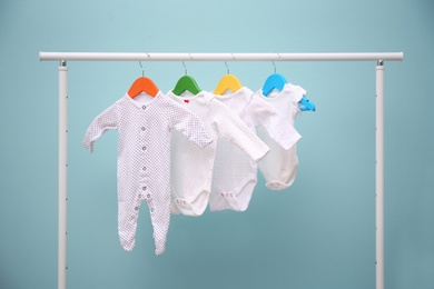 Baby clothes hanging on rack against color background