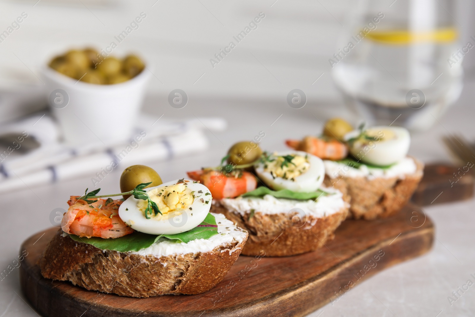 Photo of Cutting board of delicious bruschettas with shrimps on grey table