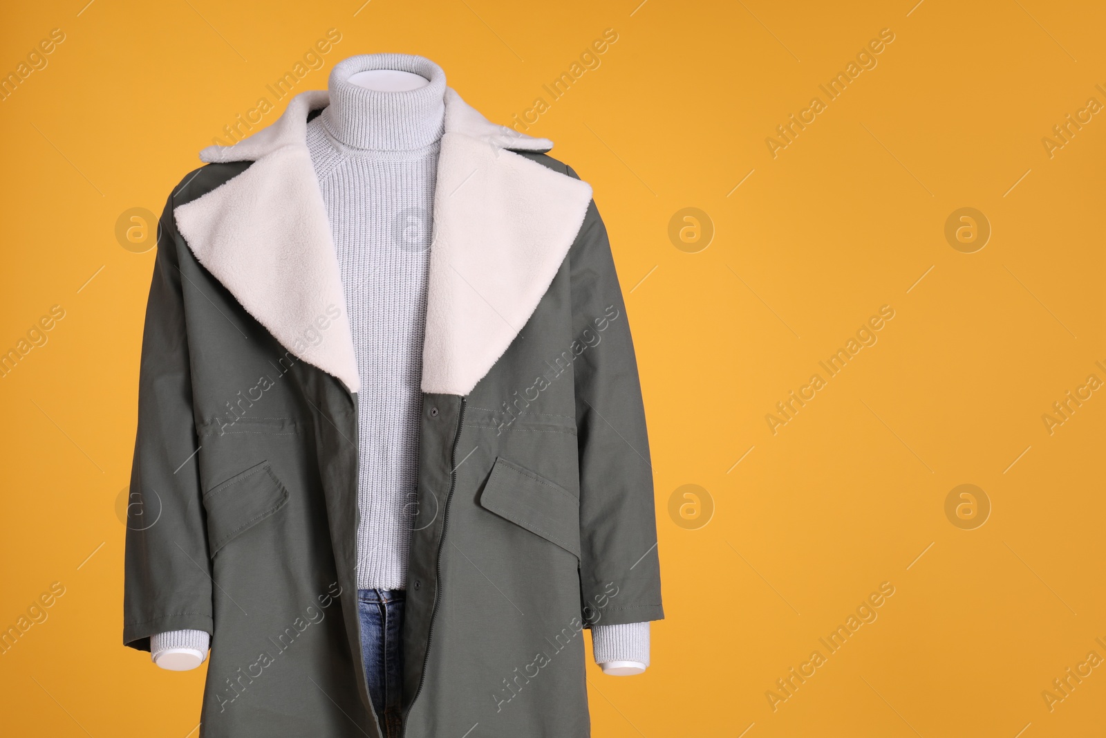 Photo of Female mannequin dressed in stylish jacket, turtleneck and jeans on orange background