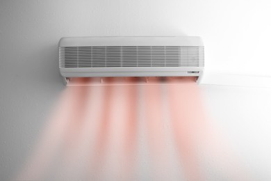 Modern conditioner and illustration of warm air flow on white wall indoors