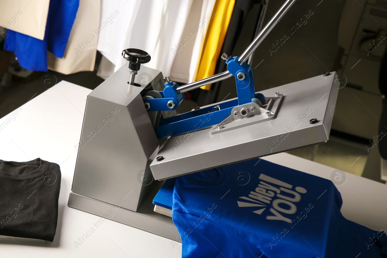 Photo of Printing logo. Heat press with blue t-shirt on white table