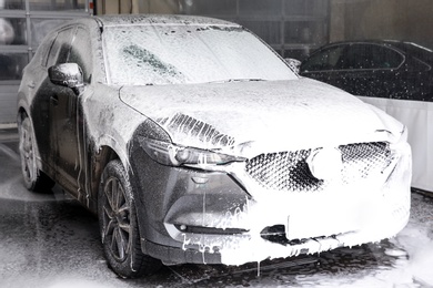 Cleaning automobile with high pressure water jet at car wash