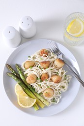 Photo of Delicious scallop pasta with asparagus, green onion and lemon served on white table, flat lay