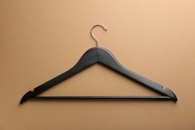 Photo of Empty black hanger on brown background, top view