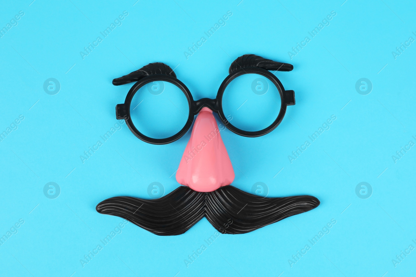 Photo of Funny mask with fake mustache, nose and glasses on light blue background, top view