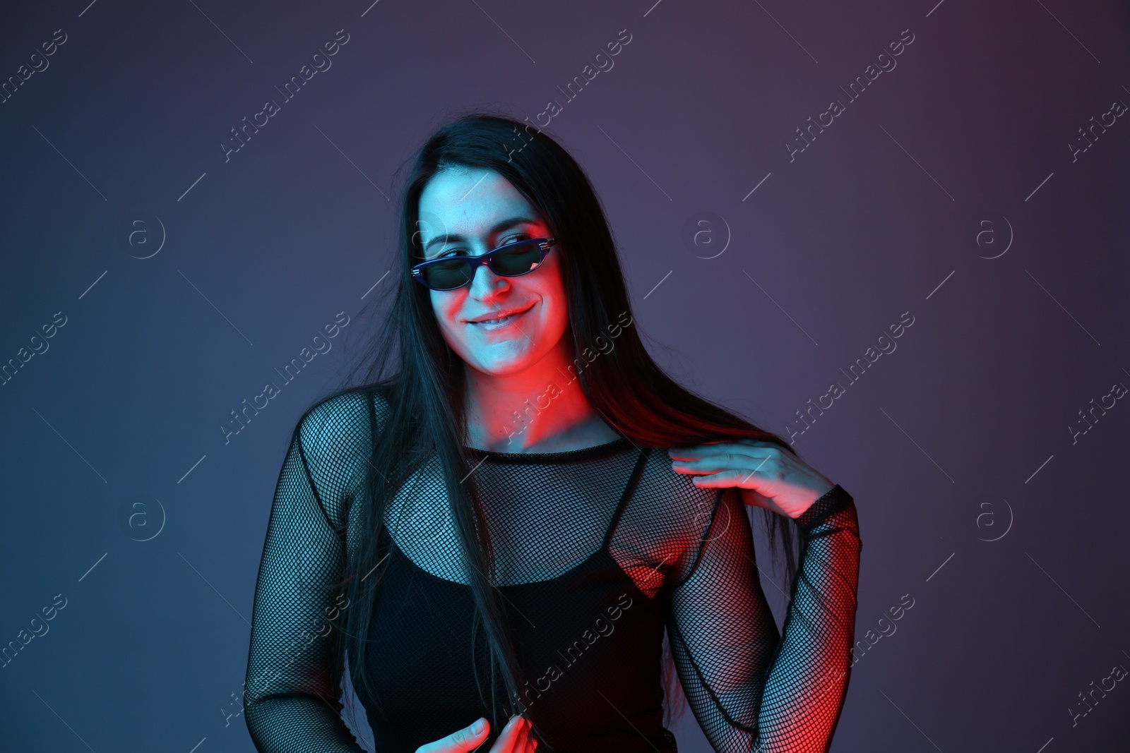 Photo of Portrait of beautiful young woman with sunglasses on color background