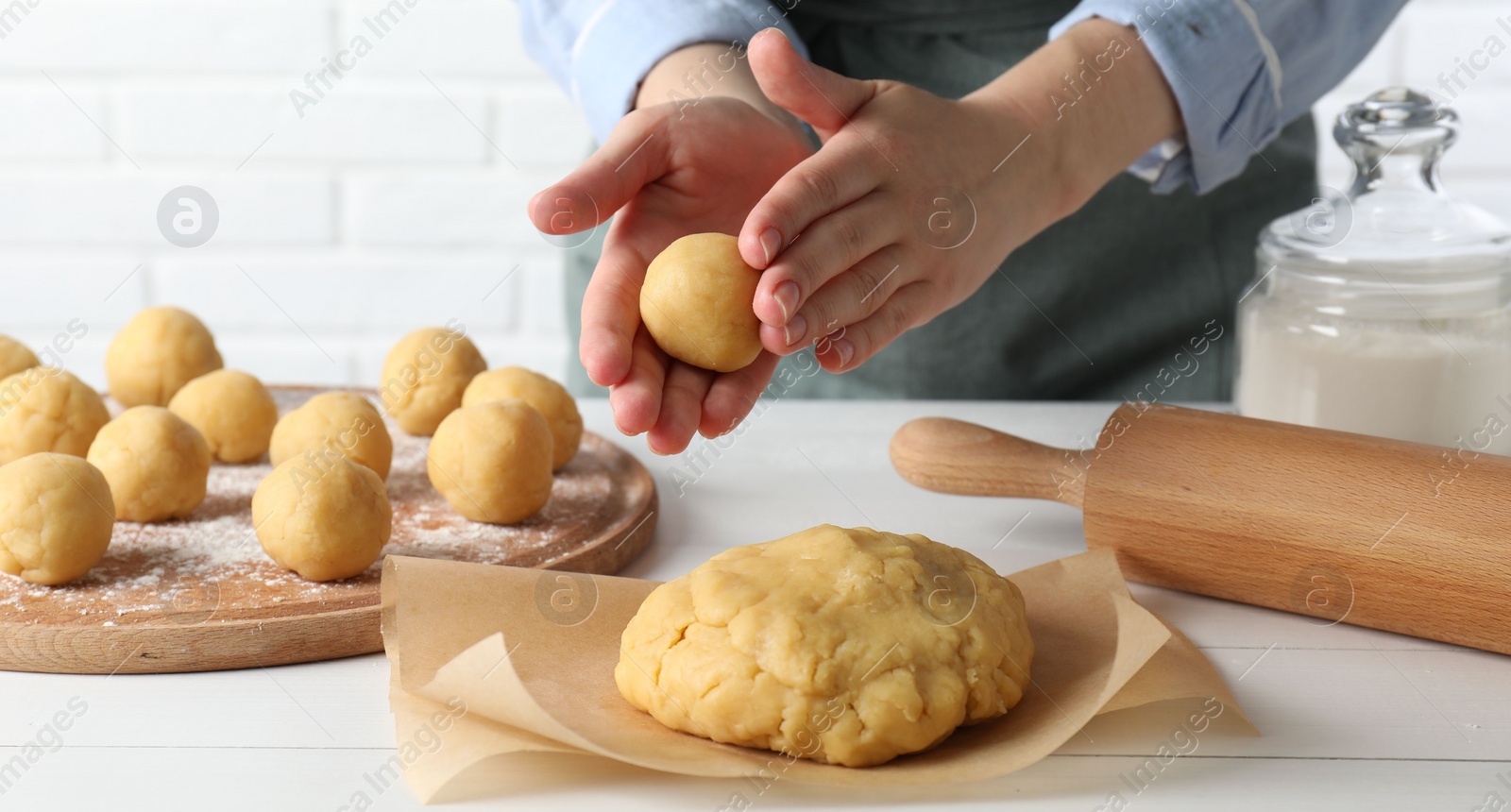 Photo of Shortcrust pastry. Woman making dough ball at white wooden table, closeup