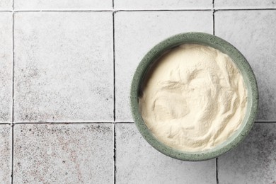 Photo of Bowl of agar-agar powder on tiled table, top view. Space for text