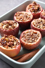 Tasty baked apples with nuts and honey in dish on table, closeup