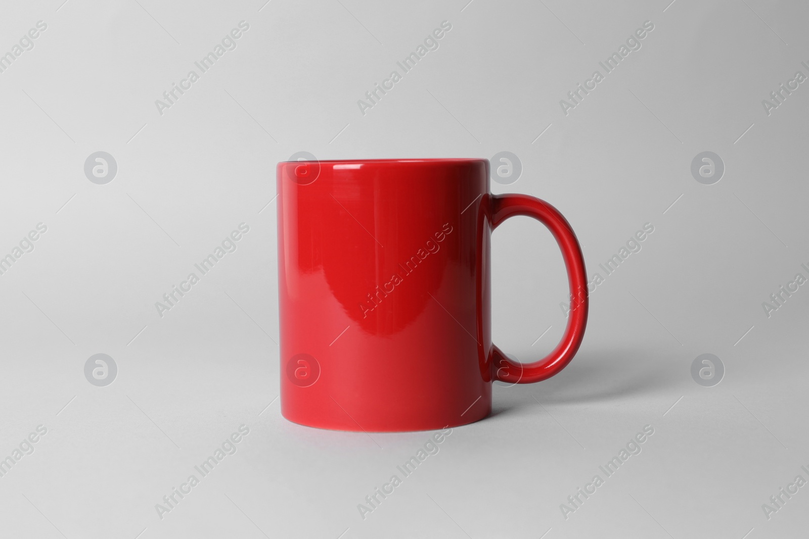 Red ceramic mug on light grey background Photo of Red ceramic mug on light grey background
