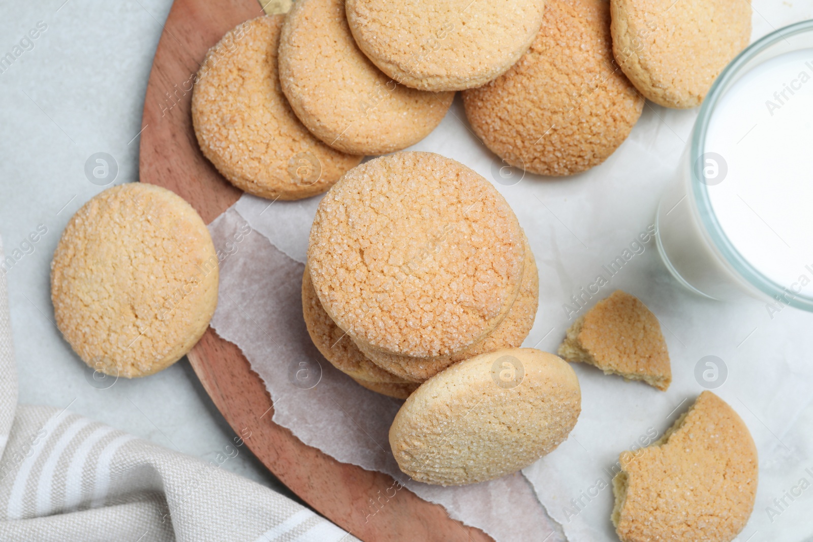 Photo of Many tasty sugar cookies and milk on light grey table, flat lay