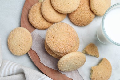 Many tasty sugar cookies and milk on light grey table, flat lay