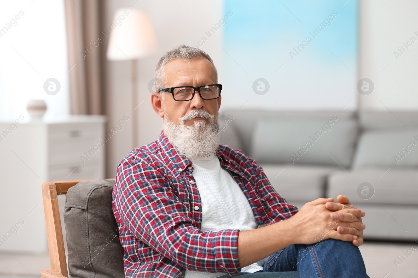 Photo of Portrait of handsome mature man with glasses sitting on chair in room