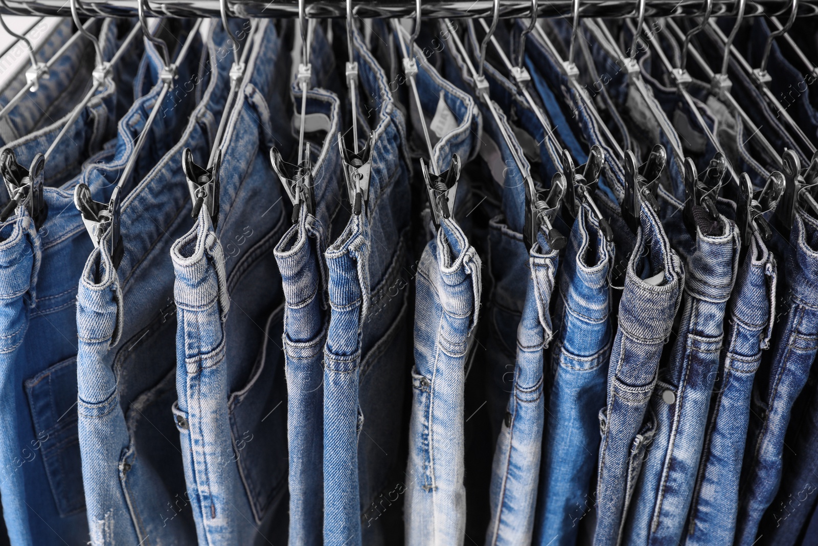 Photo of Rack with different stylish jeans as background