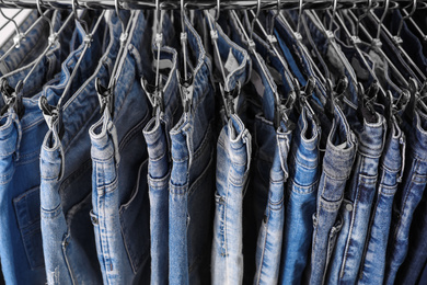 Rack with different stylish jeans as background