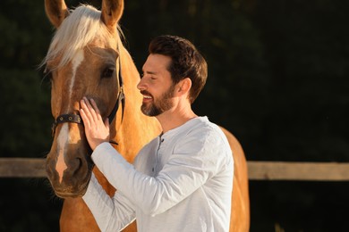 Photo of Handsome man with adorable horse outdoors. Lovely domesticated pet