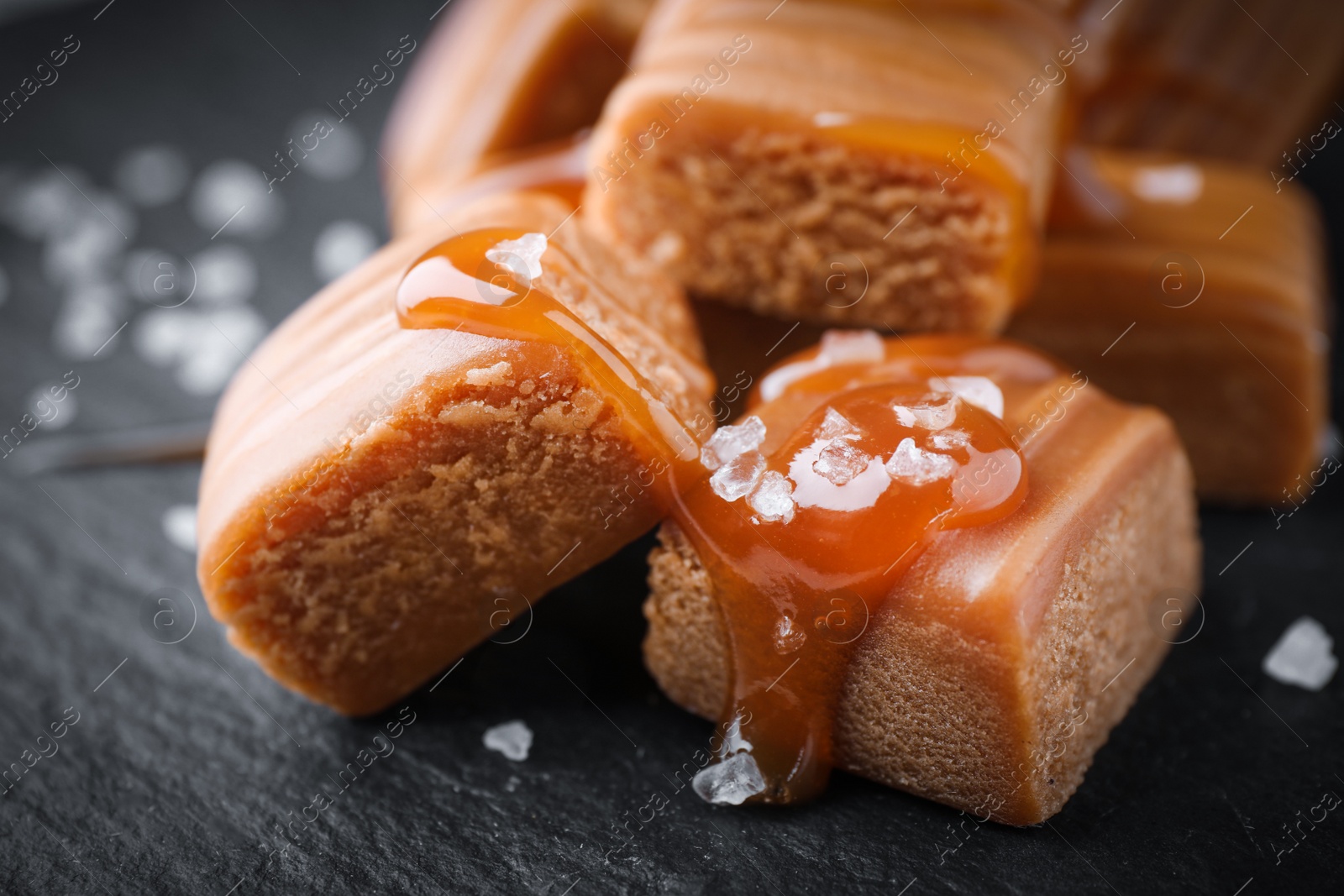 Photo of Salted caramel with sauce on black table, closeup view