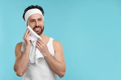 Washing face. Man with headband and towel on light blue background, space for text